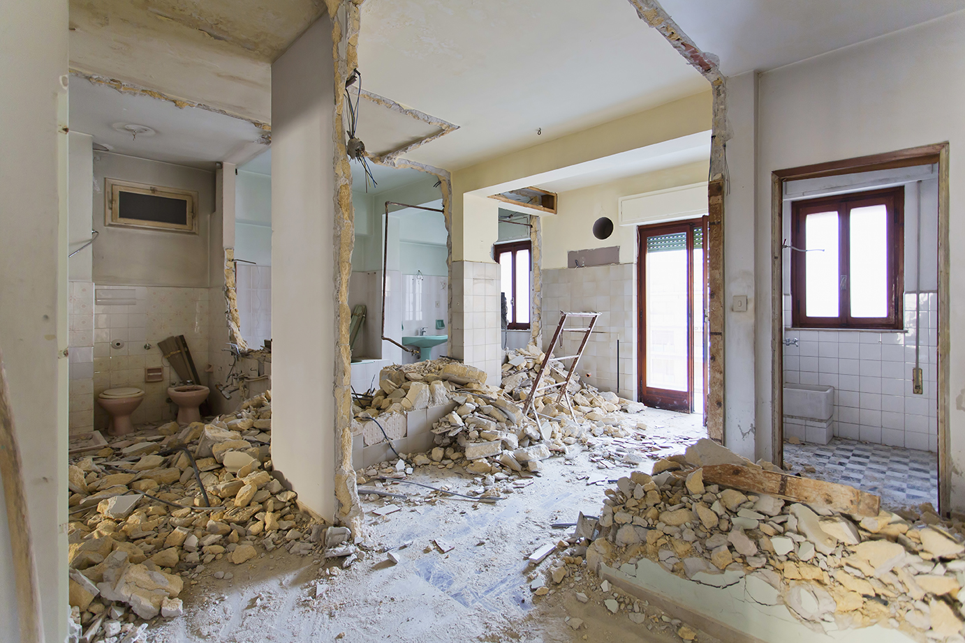 Wohnungsinnenraum mit abgerissenen Wänden und Bauschutt auf dem Boden während Renovierung oder Abbrucharbeiten.
